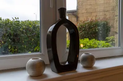 a mirror sitting on a window sill with two vases at Saughton Suite with views of Water of Leith in Edinburgh