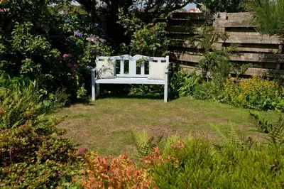 a white bench sitting in the middle of a garden at Troon Arts & Crafts Period Home Golf Beach in Troon