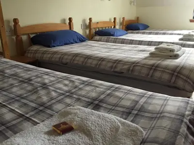 three beds in a bedroom with a book on them at Corran Bunkhouse in Onich