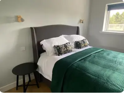 a bedroom with a bed with a green blanket and a stool at The Lodge at Muir Estate in Thornhill