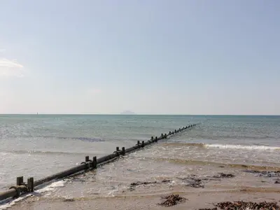 a pier stretches out into the water on a beach at Ailsa Shores in Turnberry
