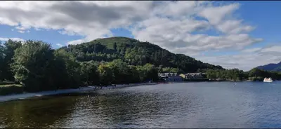 a mountain sitting on the shore of a lake at Bay Apartment in Helensburgh