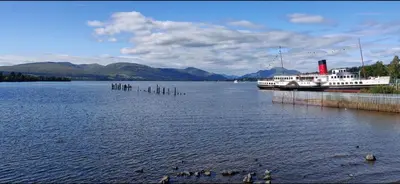 a large boat is docked on a large lake at Bay Apartment in Helensburgh