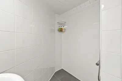 a white bathroom with a shower with a glass door at Bay Apartment in Helensburgh