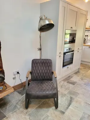 a chair in a room with a lamp and a kitchen at Loch Lomond Blair Byre in Rowardennan