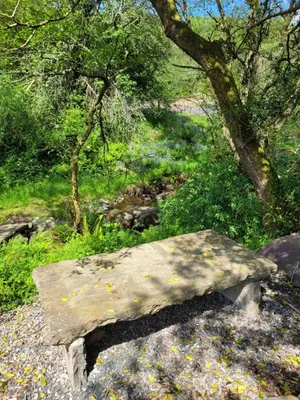 a stone bench sitting on the side of a forest at Loch Lomond Blair Byre in Rowardennan