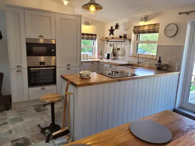 a kitchen with white cabinets and a wooden counter top at Loch Lomond Blair Byre in Rowardennan