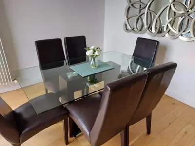 a glass dining room table with black chairs and a vase of flowers at Quartermile Luxury Landing Apartment in Edinburgh