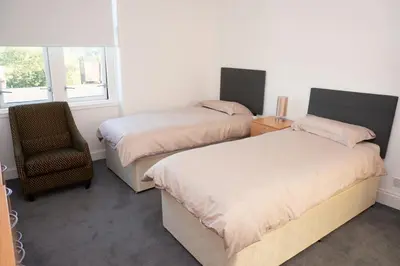 a bedroom with two beds and a chair and a window at Aberfoyle Inn in Aberfoyle