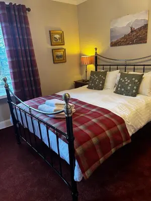a bedroom with a large bed with a blanket on it at Killean Farmhouse B&B in Inveraray