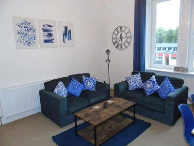a living room with two couches and a table at Snug - Sealladh Mara Apartment in Helensburgh