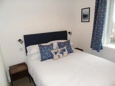 a bedroom with a bed with blue and white pillows at Snug - Sealladh Mara Apartment in Helensburgh