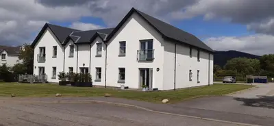 a white house with a black roof at One The Cairns in Connel