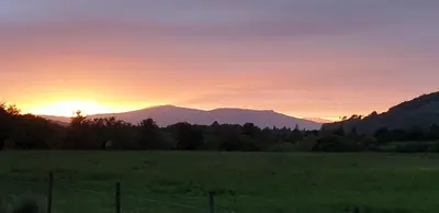 a sunset over a field with mountains in the background at One The Cairns in Connel