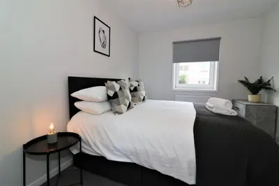 a bedroom with a large bed with a candle on a table at Signature - Caldercruix House in Caldercruix