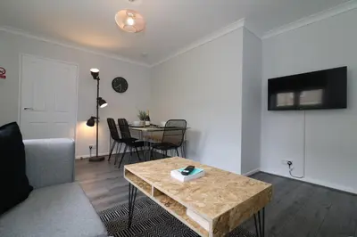 a living room with a couch and a table at Signature - Caldercruix House in Caldercruix
