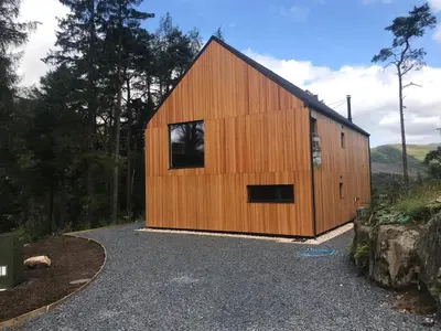 a wooden barn with a window on the side of it at An Caisteal Lodge with cascading waterfall view in Crianlarich