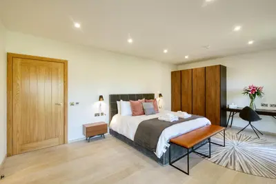 a bedroom with a bed and a table and a door at An Caisteal Lodge with cascading waterfall view in Crianlarich