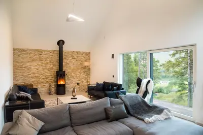a living room with a couch and a large window at An Caisteal Lodge with cascading waterfall view in Crianlarich