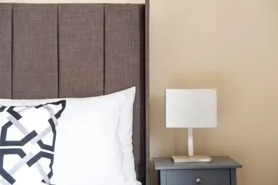 a bed with a headboard and a lamp on a night stand at Stunning 5 bedroom apt, close to city centre, SEC, Hydro and motorway in Glasgow