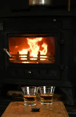 two glasses of whiskey on a table in front of a fireplace at Easdale Cottage in Oban