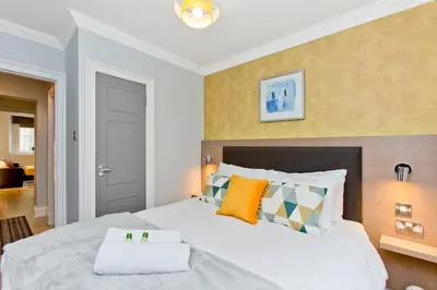 a bedroom with a large white bed with pillows at Ultra Modern, West End Village, Refurbished basement appt in Edinburgh