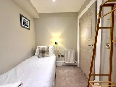 a small bedroom with a white bed and a lamp at Modern 3 Bedroom Apartment, West End in Edinburgh