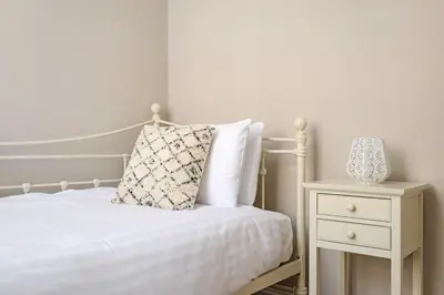a white bed with a pillow and a night stand at The Rose Street Retreat by Calton Living in Edinburgh