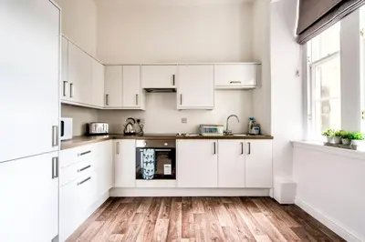 a kitchen with white cabinets and a wooden floor at Lothian Road - perfect city centre location. in Edinburgh