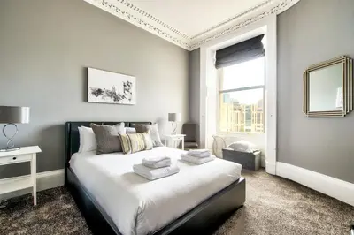 a bedroom with a bed with white sheets and a window at Lothian Road - perfect city centre location. in Edinburgh