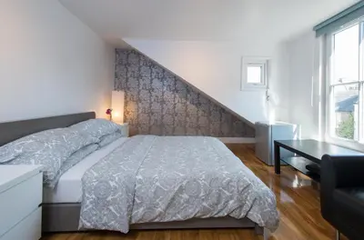 a white bedroom with a bed and a staircase at 7 Bedroom Townhouse in Edinburgh