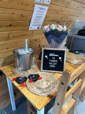 a table with wine glasses and a sign on it at Timber Valley Pods in Galston