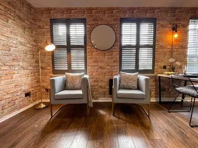 a living room with two chairs and a brick wall at Studio Hart Castle Rock Grassmarket in Edinburgh
