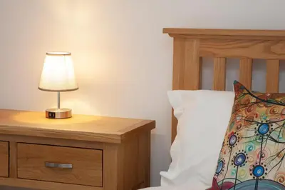 a lamp on a night stand next to a bed at 5 bed house near Oban in Oban