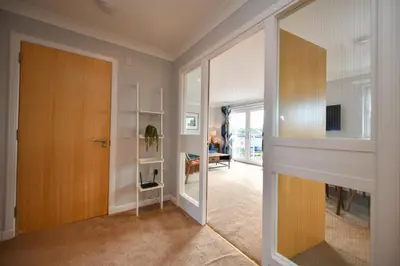 a hallway with a wooden door and a living room at Troon Executive Apartment in Troon