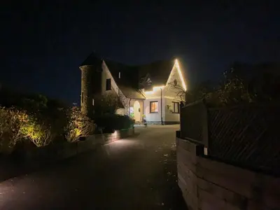 a white house with lights on the side of it at night at Corrie House in Craobh Haven