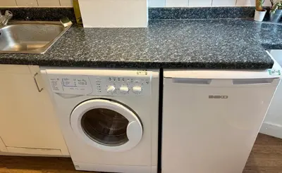 a white washing machine in a kitchen next to a sink at Bread street, Central and spacious one bed flat in Edinburgh