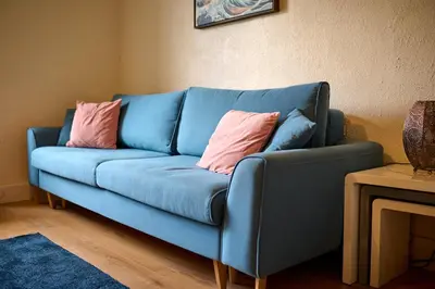 a blue couch with two pink pillows on it at Charming Apt nr Centre - Terrace & Street Parking in Oban
