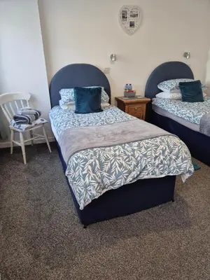 a bedroom with two beds with blue pillows and a chair at Firthview House in Kirn