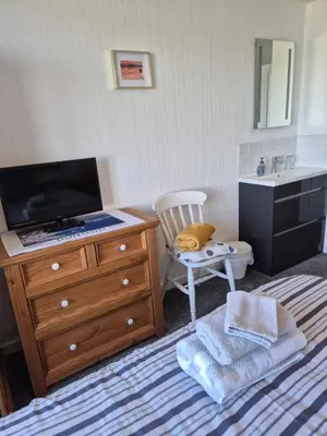 a bathroom with a television and a dresser with a sink at Firthview House in Kirn