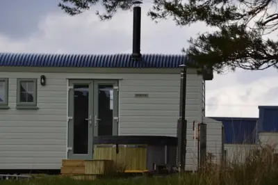 a white house with a door in front of it at Corriemuckloch Unique Huts in Dunkeld
