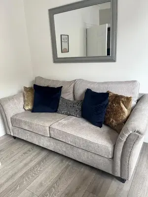 a couch with pillows in a living room with a mirror at Carrick - One Bed Apartment in Largs