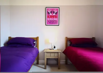 two beds in a room with purple sheets and a table at Forth View Apartment in Stirling
