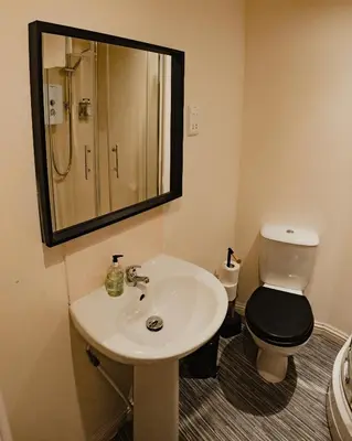 a bathroom with a sink and a toilet and a mirror at Royal Chambers Serviced Apartments in Glasgow