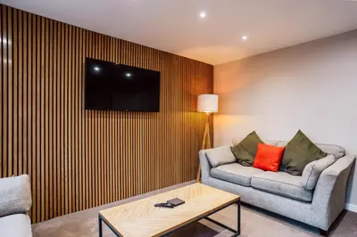 a living room with a couch and a tv on a wall at Dalmarnock Stay in Glasgow