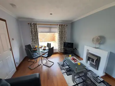 a living room with a table and a fireplace at PREMIER - Kenilworth House in Holytown