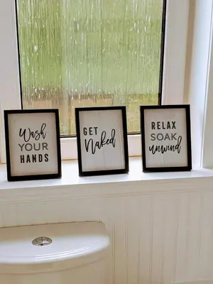 three framed pictures on a window sill above a toilet at Glenclova - No 5 Bellyeoman, bright two bedroom apartment in Fife