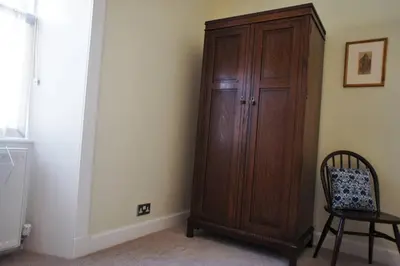 a wooden cabinet in a room with a chair at 17 William Street in Helensburgh