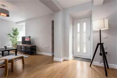 a white living room with a table and a lamp at Shore View - Donnini Apartments in Prestwick