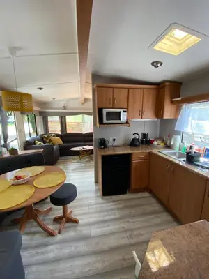 a kitchen and living room with a table and a couch at Unique Caravan with Outdoor Space in Ballantrae
